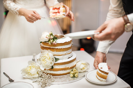 Bride and groom at wedding reception cutting the wedding cake with flowers.の写真素材