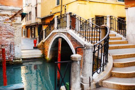 Canal in Venice, Italy and colorful buildings with a pedestrian bridge.の写真素材