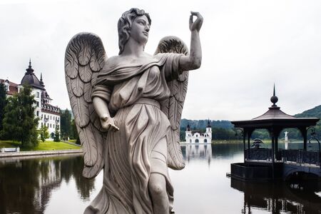 House and stone statue in a forest on a lakeの写真素材