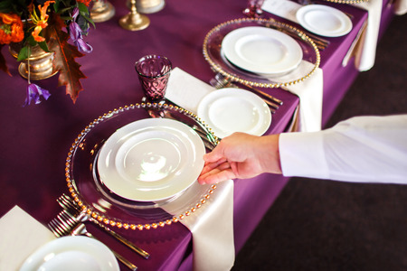 The waiter puts the plate on the table.