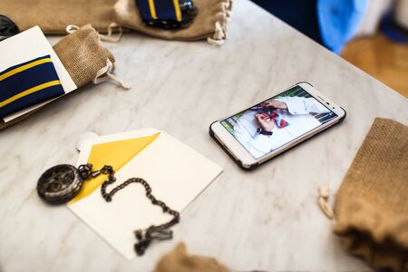 Vintage watch, phone and bow-tie on the table. Wedding preparation.