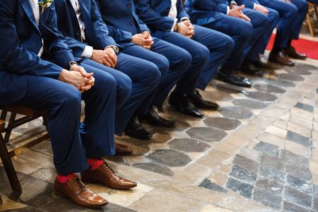 Stylish groomsmen sit during the ceremony in the church.の写真素材