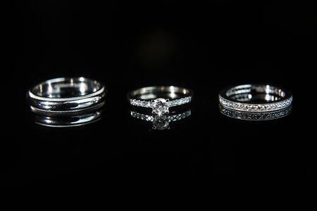 Three wedding rings on the reflecting black surface.の写真素材