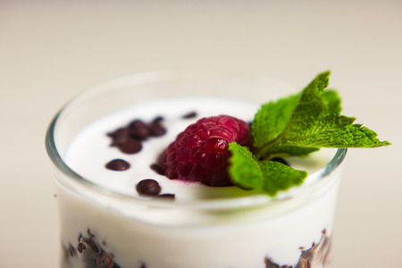 Yogurt with cream, raspberries served in glass on white background