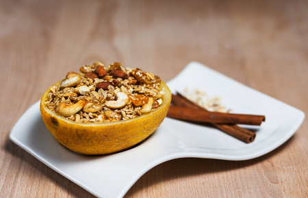 Homemade granola in a plate of melon on wooden tableの写真素材