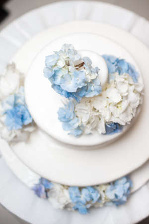 White wedding cake with blue flowers on a table.の写真素材