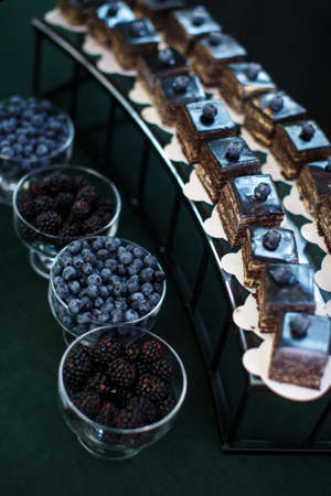 Rows of desserts on the wedding table and bowls with berries.