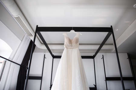 Wedding dress hanging over the bed in the hotel roomの写真素材