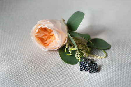 Cufflinks of the groom on the background of a boutonniere.