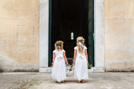 Little bridesmaids stand in front of the entrance to the church.の写真素材