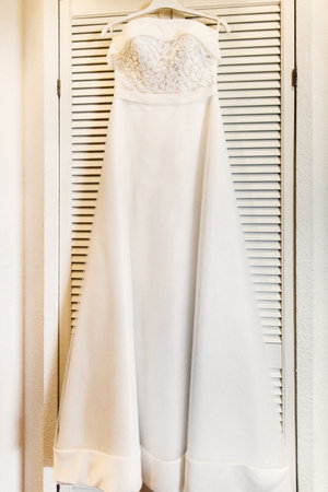 Wedding dress hanging on a wooden wardrobe.の写真素材