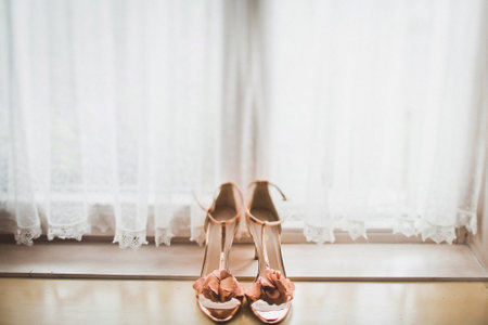 Pink wedding shoes on a wooden windowsill.の写真素材