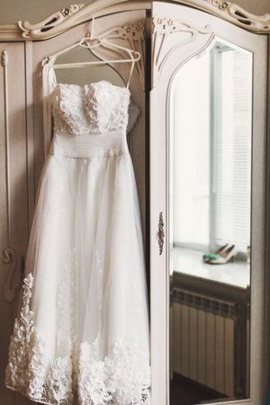 Wedding dress hanging on a white wardrobe.