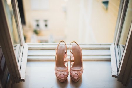 Pink wedding shoes on a wooden windowsill.の写真素材