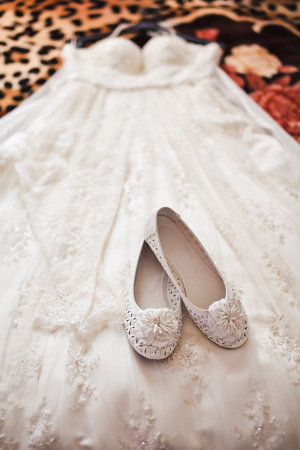 White shoes lie on a wedding dress.の写真素材