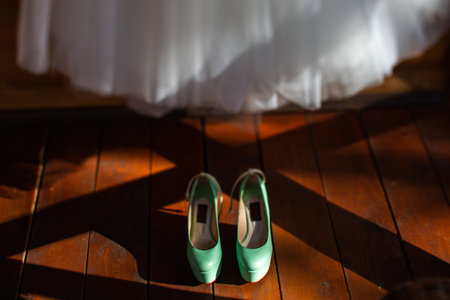 Turquoise wedding shoes stand on a wooden floor.の写真素材