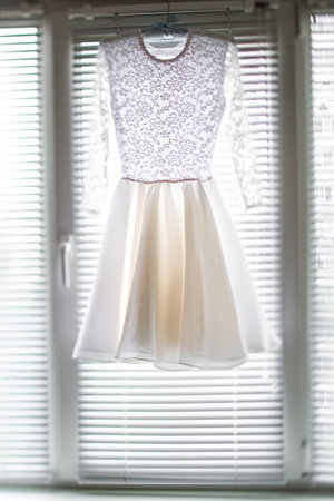 Short wedding dress hanging on the window.の写真素材