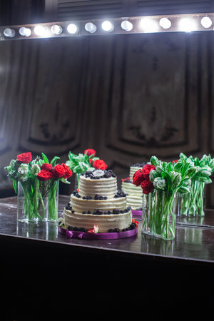 Bouquets in vases and a wedding cake decorated with berries.の写真素材