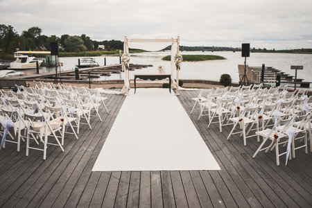 Outdoor wedding ceremony on a wooden pier near the lake.の写真素材