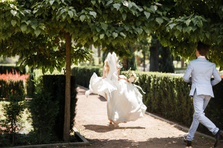 Bride and groom on their wedding day. The groom runs after the brideの写真素材