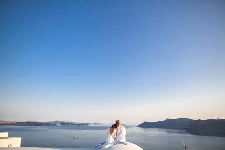 Bride and groom on their wedding day. Newlyweds sit on the roof in an embraceの写真素材