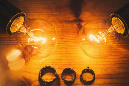 Three wedding rings and two light bulbs on the table.の写真素材