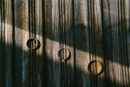 Three wedding rings on a wooden striped board.の写真素材