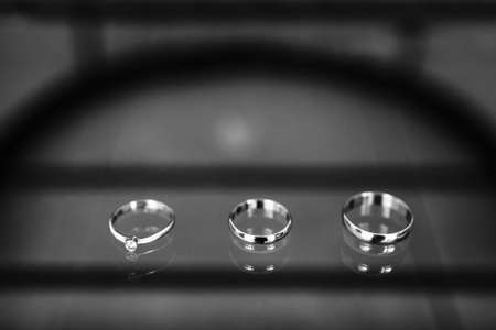 Three wedding rings on a glass surface.の写真素材