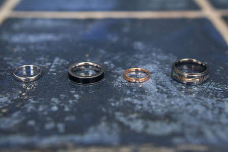 Four wedding rings on a blue tile.の写真素材