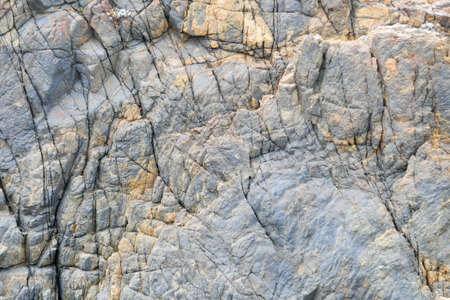 Photo of some weathered eroded cracked rocks on the coastline