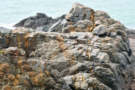 Photo of some weathered eroded cracked rocks on the coastline