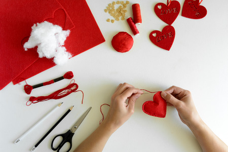 Valentine's day felt crafts. Woman hands sewing red hearts. DIY. Flat lay. Top viewの写真素材