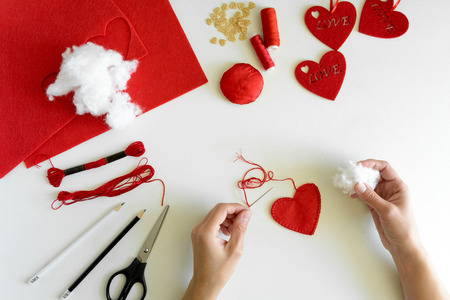 Valentine's day felt crafts. Woman hands sewing red hearts. DIY. Flat lay. Top viewの写真素材