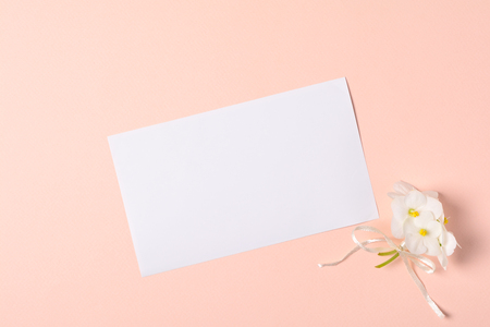 Bouquet of violet flowers (viola) and empty greeting card on pink paper background. Valentine's day celebration concept. Top view. Flat lay. Mock-upの写真素材