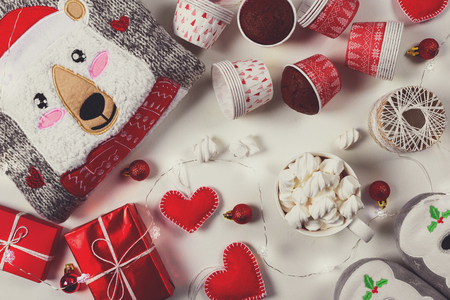 Christmas presents. Knitted sweater, slippers, gift boxes, chocolate muffins and hot chocolate with marshmallow laid on a white wooden table background. Flat lay. Top view. Tonedの写真素材