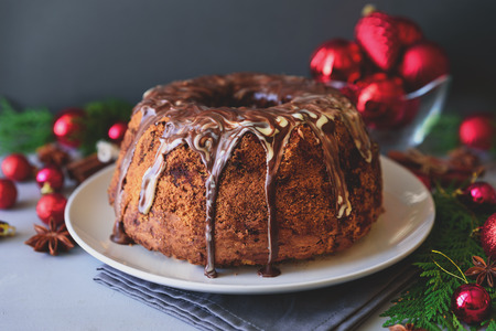 Christmas cake with chocolate icing on gray wooden background. Holiday decorations concept. Tonedの写真素材