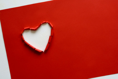 Ripped paper hole heart shaped on red paper background. Valentine's day celebration conceptの写真素材