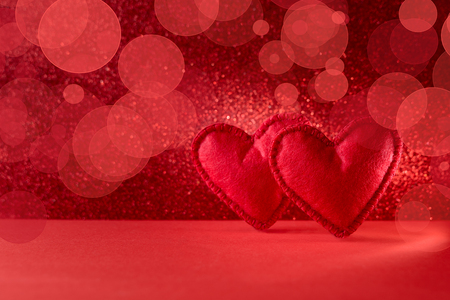 Felt hearts on red background with bokeh. Valentine's day celebration or love concept. Copy spaceの写真素材