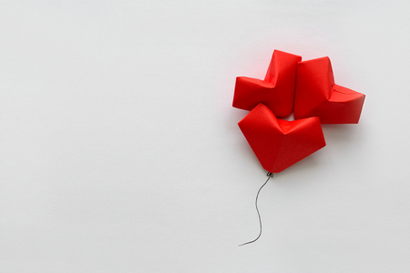 Valentines day card. Red paper heart shape balloons on thread. Origami and minimalist conceptの写真素材