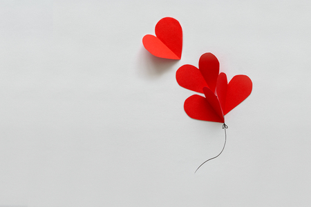 Valentines day card. Red paper heart shape balloons on thread. Paper cut style and minimalist conceptの写真素材