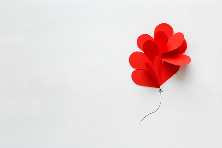 Valentines day card. Red paper heart shape balloons on thread. Paper cut style and minimalist conceptの写真素材