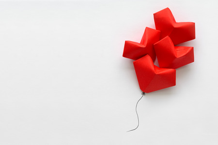 Valentines day card. Red paper heart shape balloons on thread. Origami and minimalist conceptの写真素材