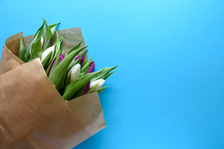 Bouquet of white and purple tulips on blue background. Top view. Flat lay. Copy space. Valentines day, mothers day, birthday, wedding celebration concept.の写真素材