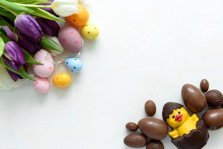 Tulips, chocolate Easter eggs and duck on white wooden background. Flat lay. Top view.の写真素材