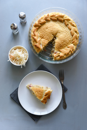 Slice of homemade sauerkraut pie on gray wooden table. Cabbage cake tradition russian foodの写真素材