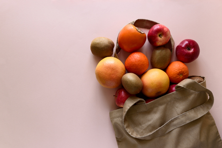 Cotton bag with differnt fruits on pink background. Ecology pack for free plastic shopping. Top view. Flat layの写真素材