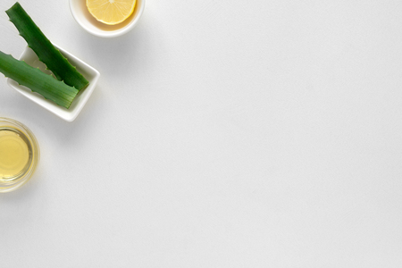 Fresh ingredients for homemade effective acne remedies on white background. Honey, sea salt, egg yolk, olive oil, oat, lemon and aloe. Flat lay. Copy spaceの写真素材
