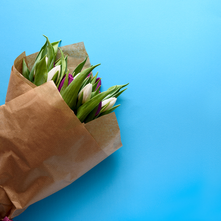 Bouquet of white and purple tulips on blue paper background. Top view. Flat lay. Copy space. Valentines day, mothers day, birthday, wedding celebration concept.の写真素材