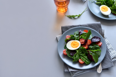 Salad mix with spinach, arugula,beet leaves, tomatoes and eggs on gray wooden background. Vegetarian food concept. Selective focus.の写真素材