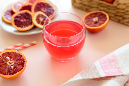 Glass of fresh blood orange juice on pink background. Selective focusの写真素材